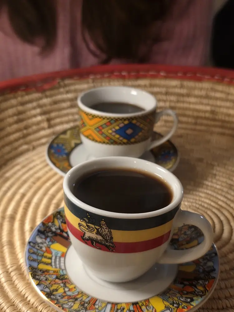 Two cups of Ethiopian coffee in traditional patterned cups on a woven tray