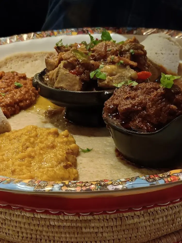 Meat sharing platter with stews served on injera in a decorated dish